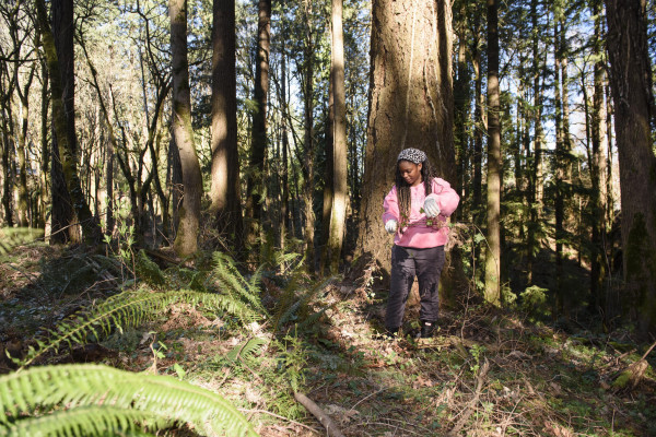 A student pulls ivy from the ground while wearing gloves.