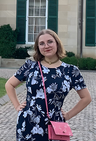Isabel posing outside with her hands on her hips, wearing a floral navy blue dress.